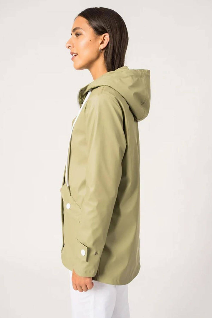 Femme portant le ciré imperméable Ste Gaia, couleur olive, avec capuche et coupe moderne.