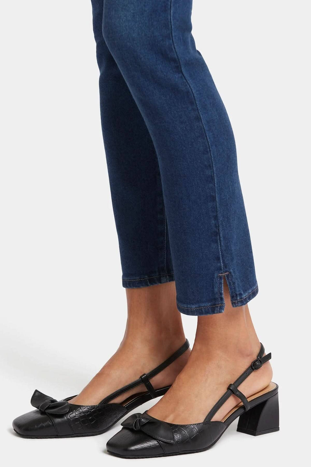 Sandales à talons carrés noires avec un nœud, portées avec un jean bleu. Élégance et confort.