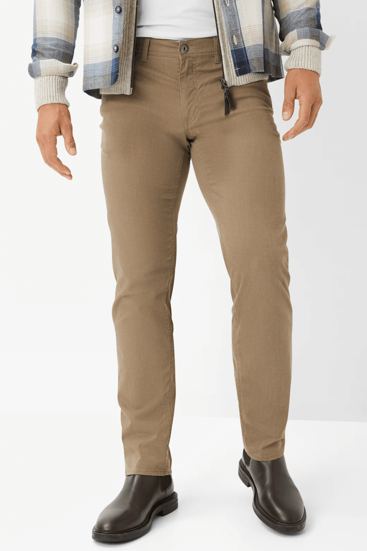 Jean Cooper homme beige avec coupe droite, porté avec des bottes, style moderne et élégant.