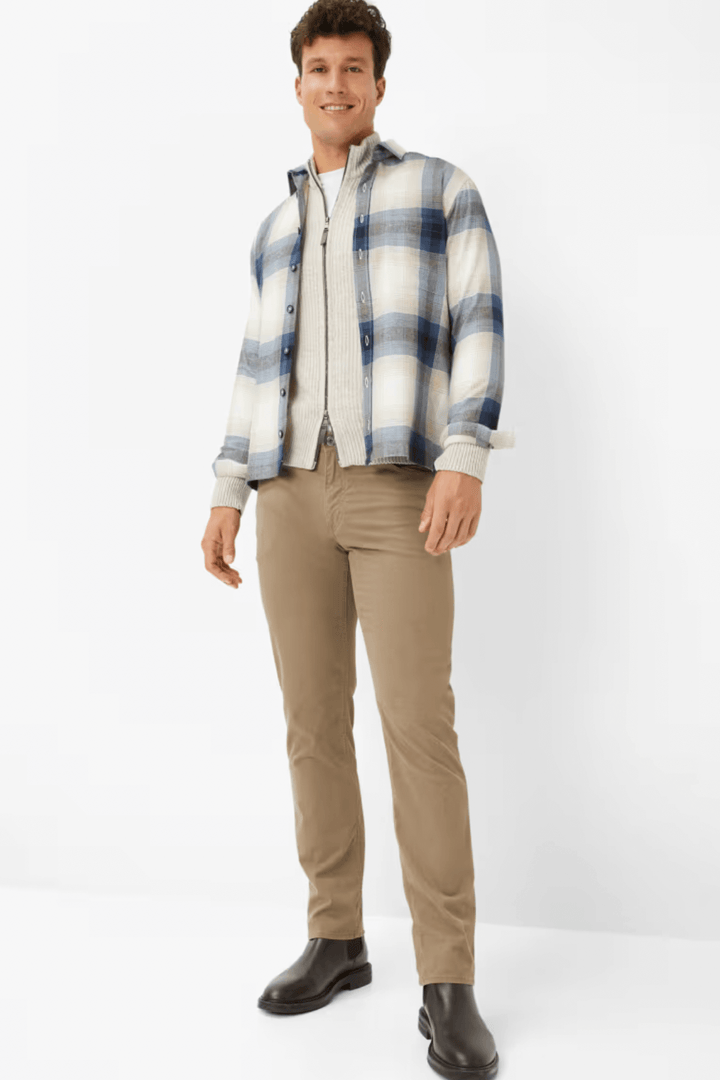 Homme en chemise à carreaux bleus et pantalon beige, style décontracté, look moderne et élégant.