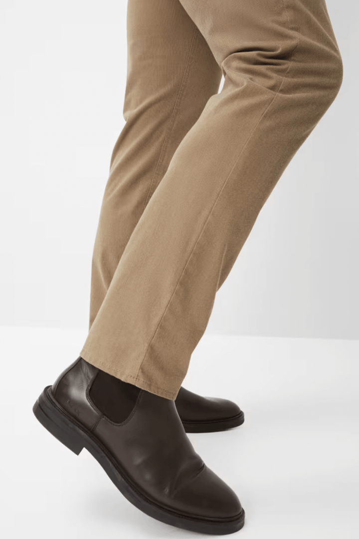 Pantalon beige avec des chaussures noires en cuir élégantes, offrant un style moderne et décontracté.