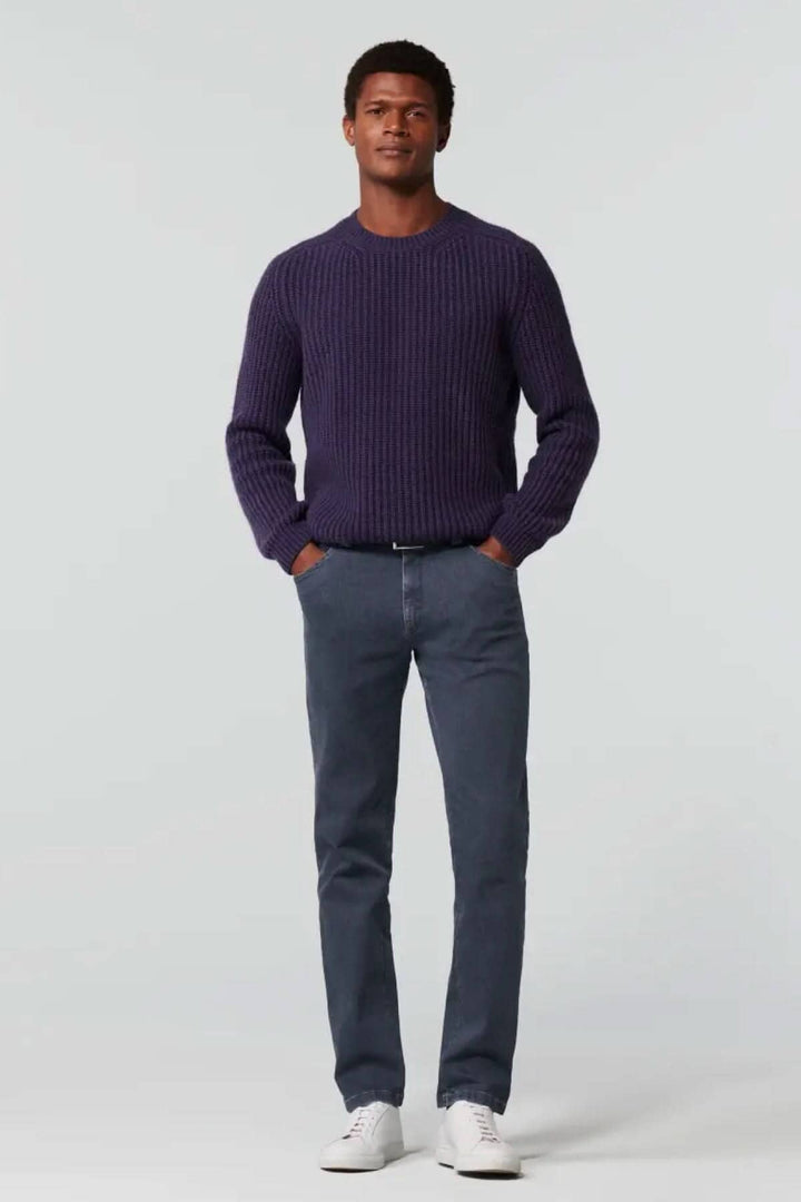 Homme portant un pull en maille violet et un jean slim en denim, avec des baskets blanches. Look décontracté et élégant.