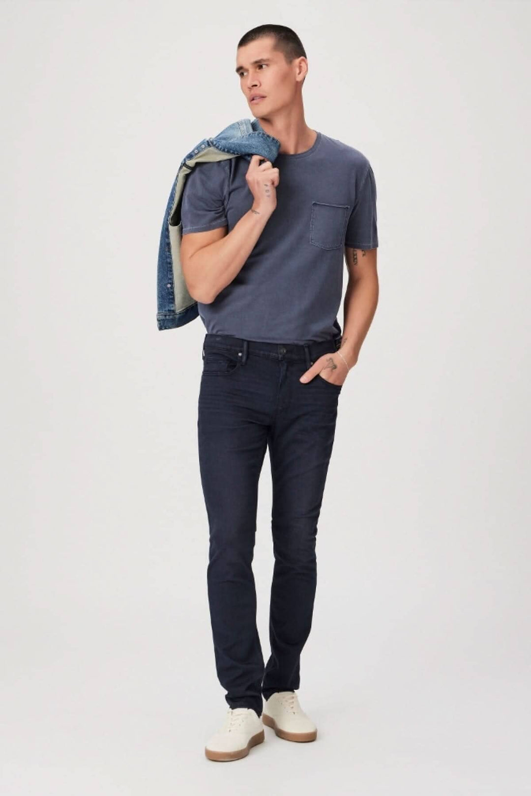 Homme portant un t-shirt gris et un jean foncé, avec une veste en jean sur l&