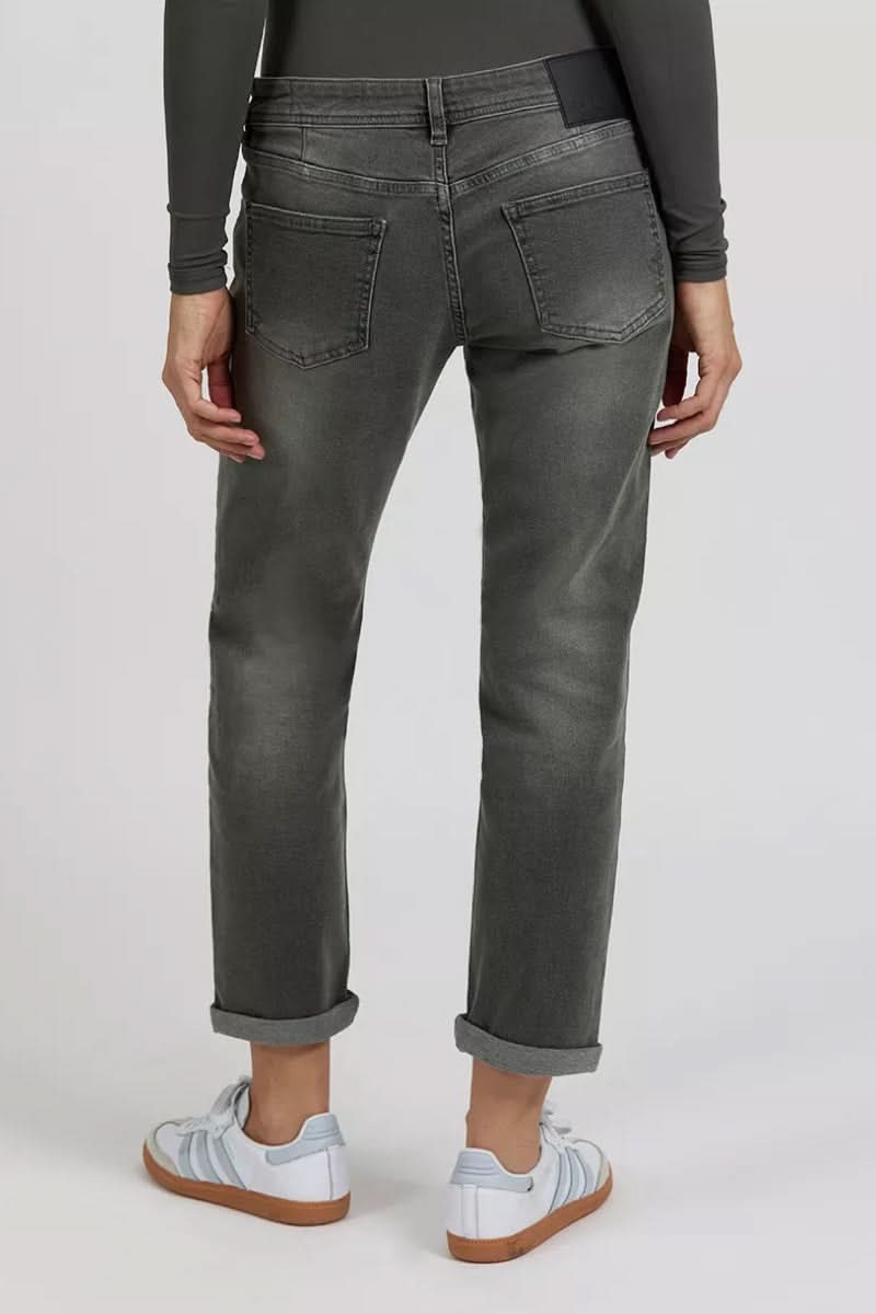 Pantalon skinny gris avec poches arrière, porté par une femme en manches longues, style décontracté.