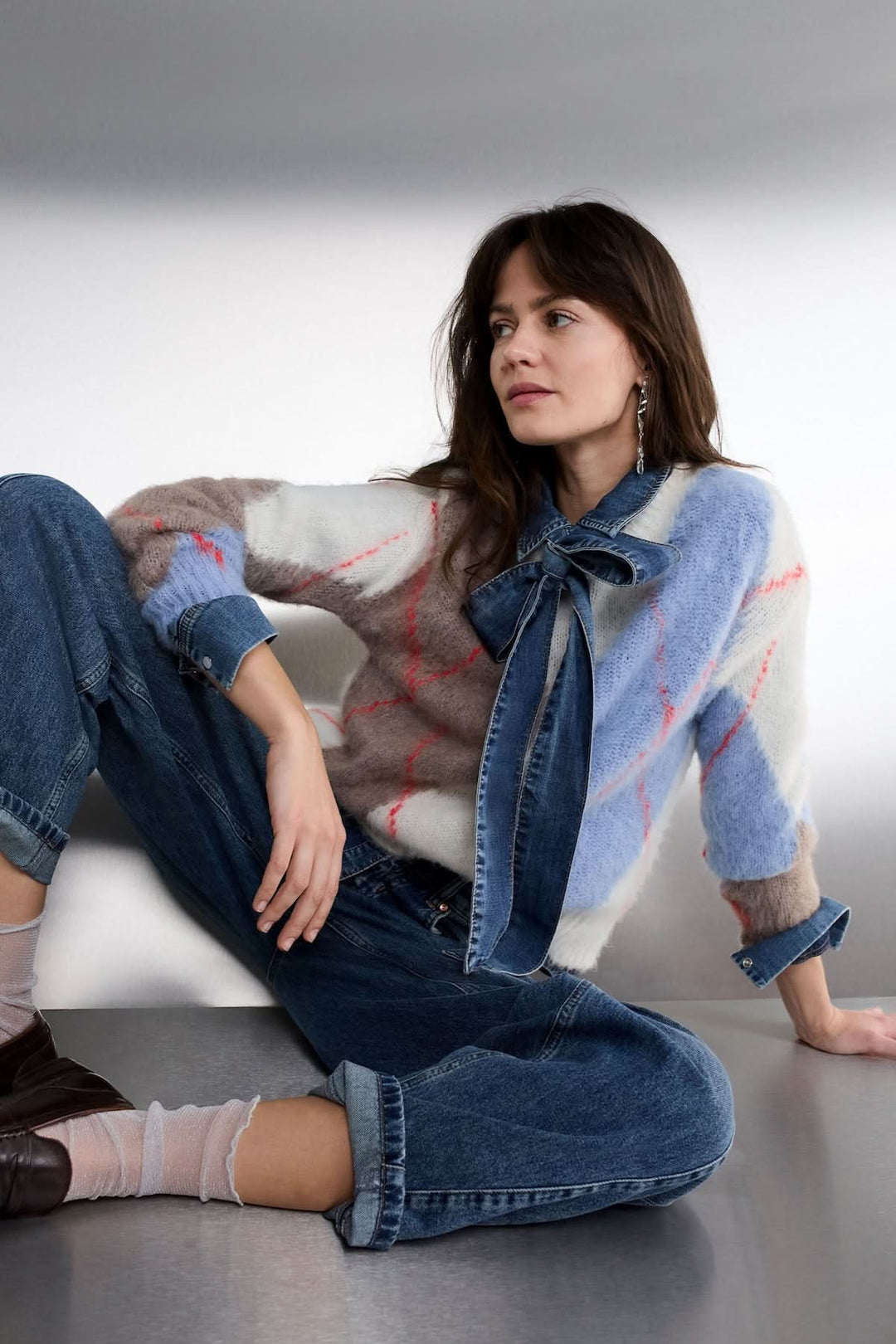 Modèle portant un jean baril taille haute avec un pull à motifs, ajoutant une touche casual chic au look moderne.