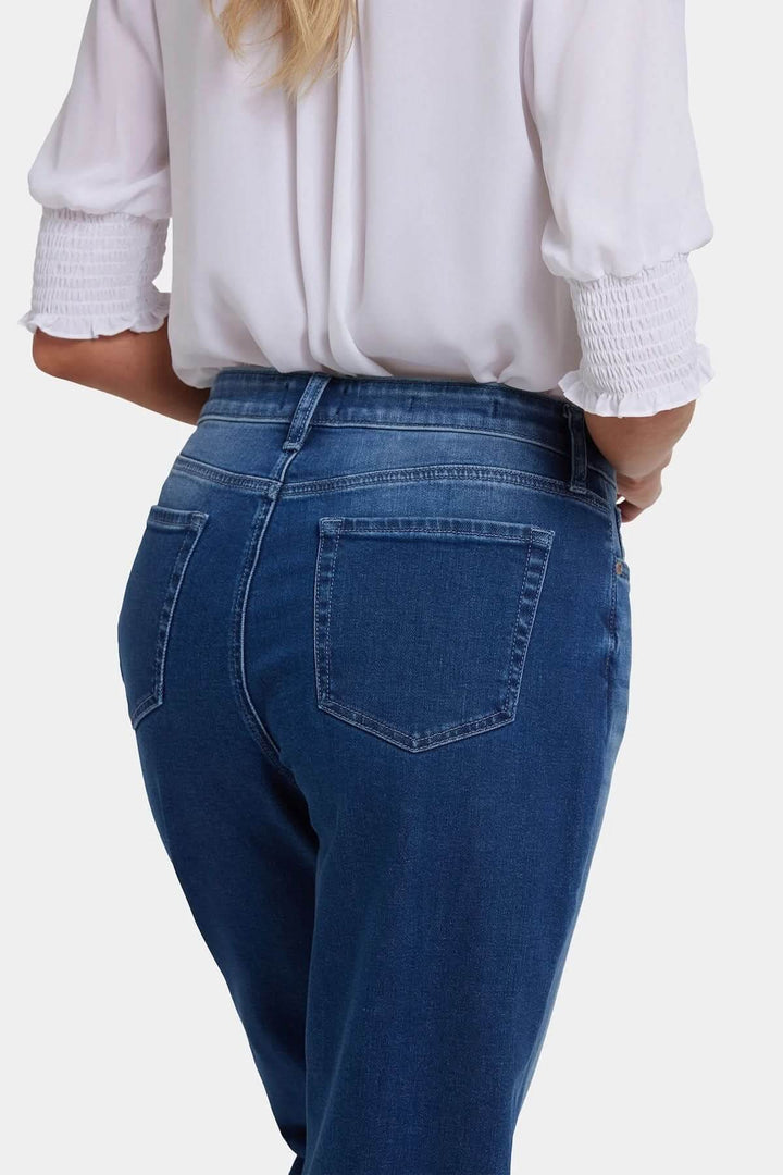 Jean boyfriend bleu délavé, coupe droite confortable, porté avec une chemise blanche, idéal pour un look décontracté et polyvalent.