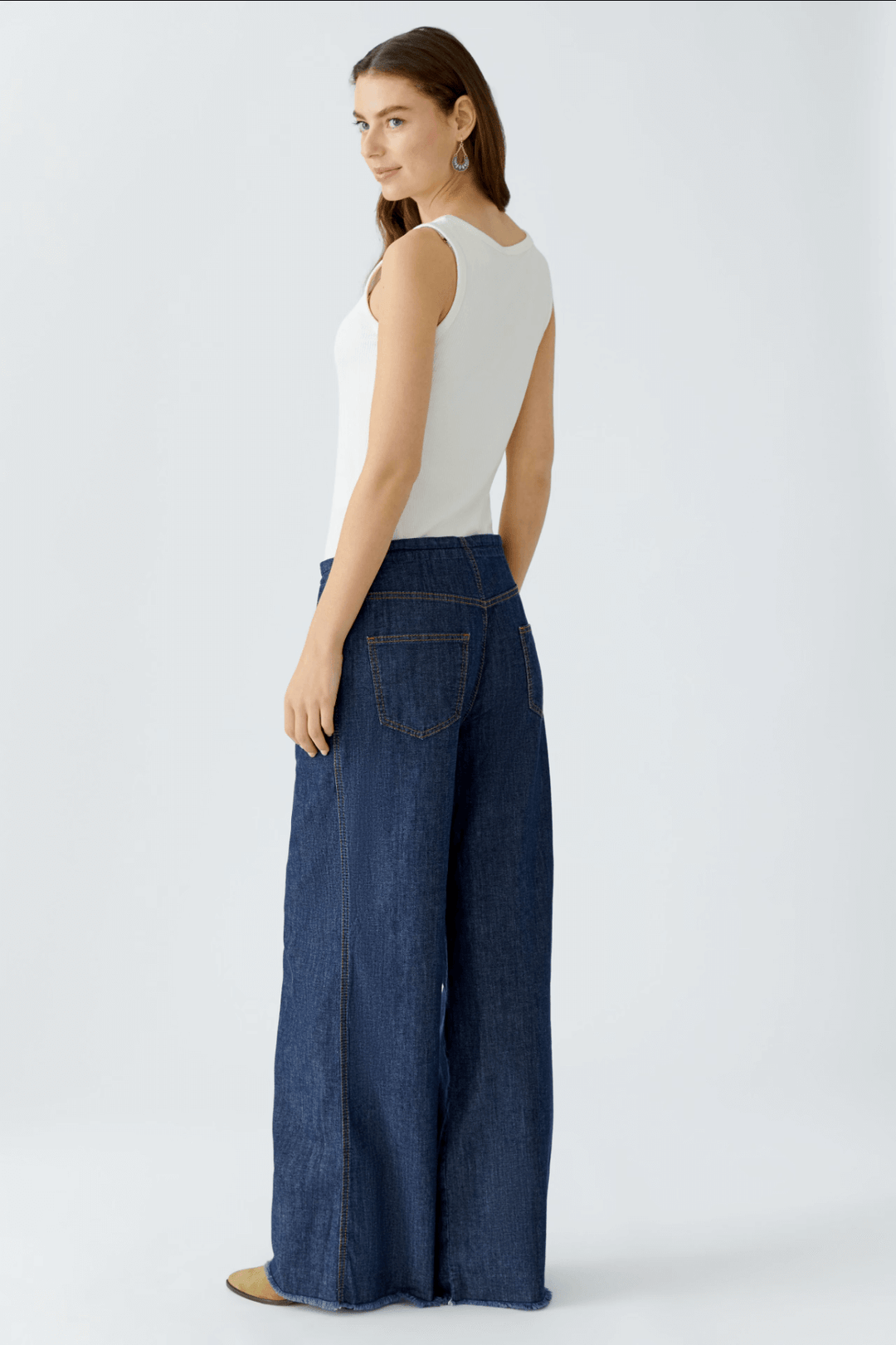Femme portant un jean ultra léger à taille mi-haute avec coupe ample et ceinture à cordon devant fond blanc.