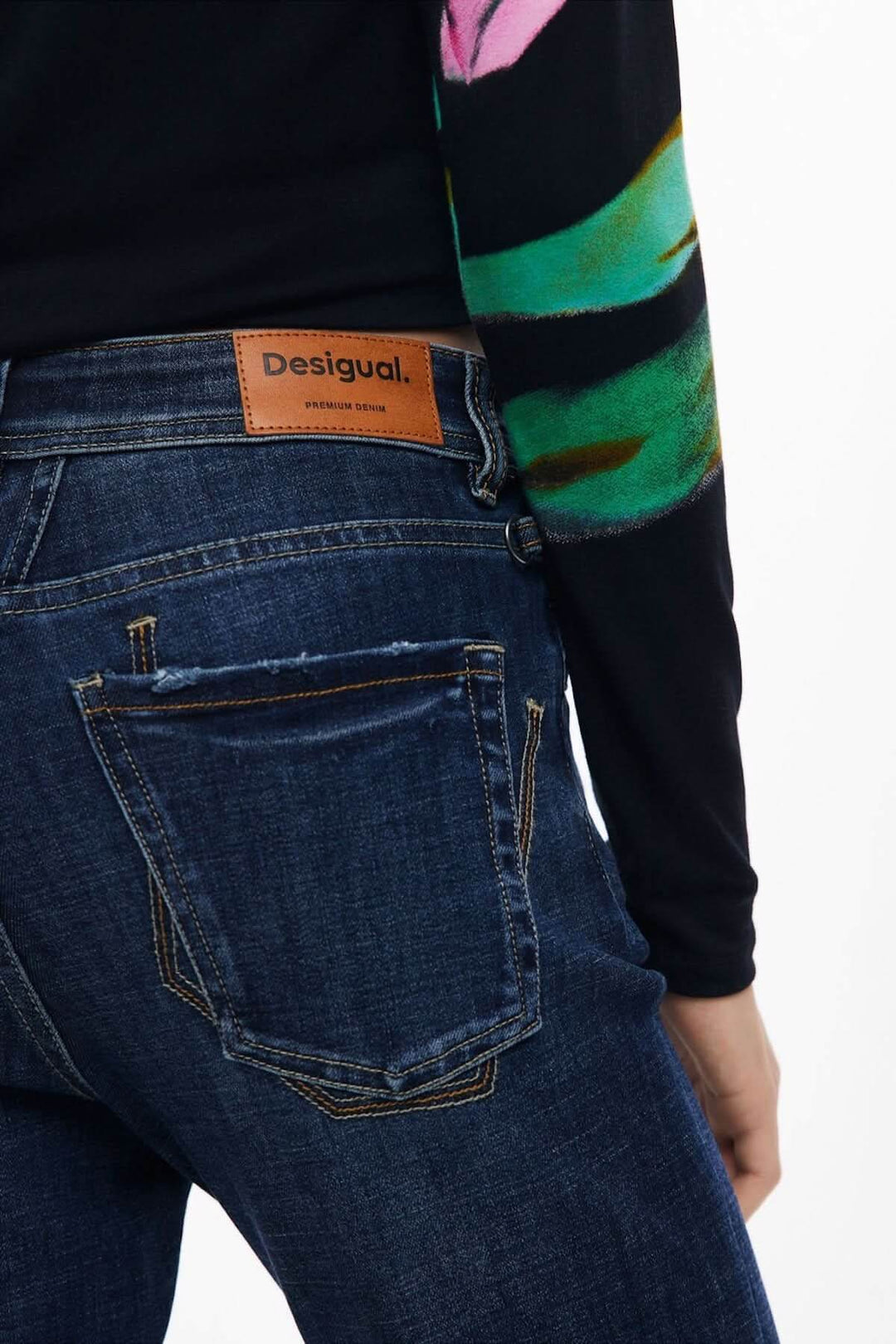 Vue arrière du jean évasé foncé avec surpiqûres contrastantes et patch logo en cuir marron.
