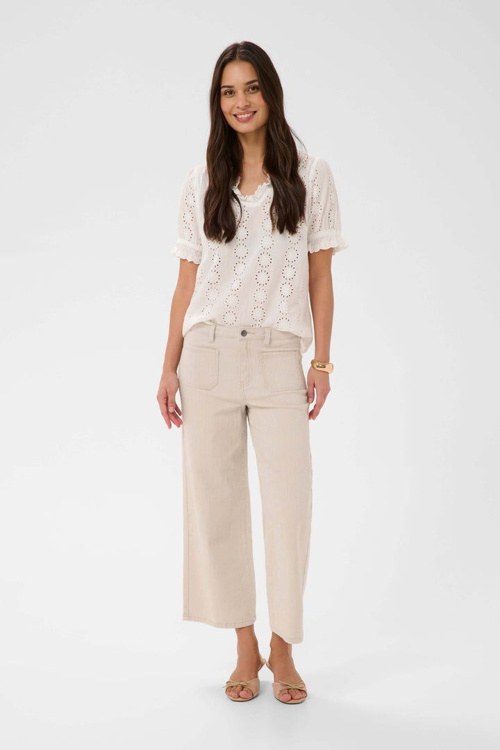 Woman wearing Jeans Brook, straight-leg jean with high waist, ankle length, pairing with a white crochet top for a casual look.