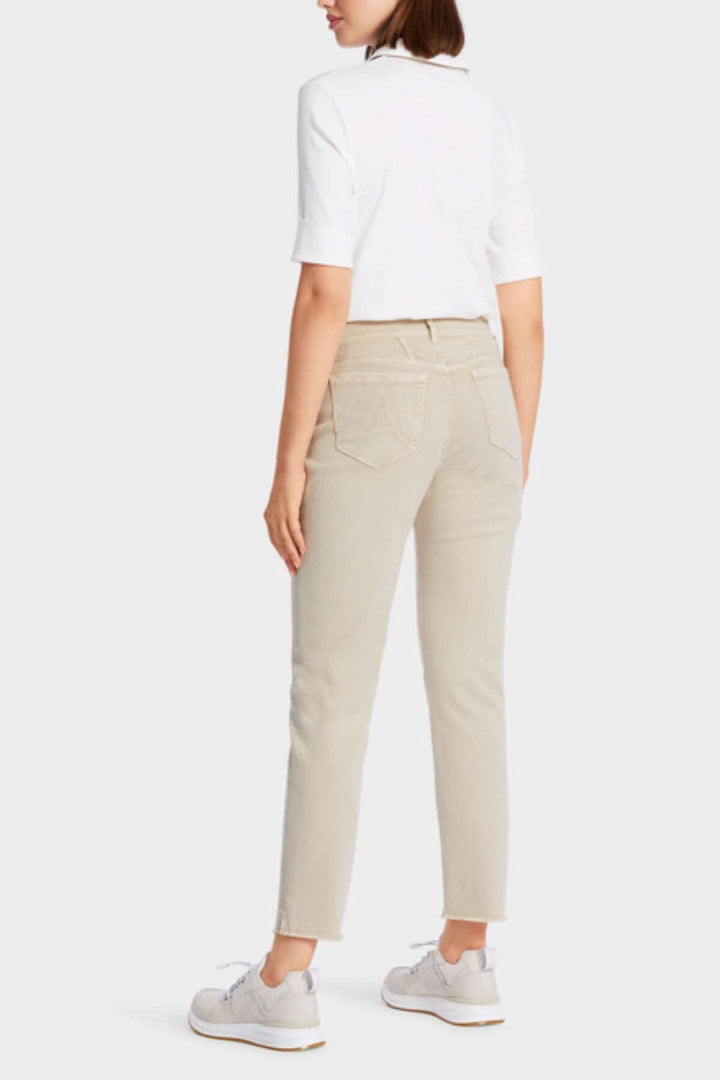 Femme portant des jeans SIKAR beige avec une blouse blanche et des chaussures blanches, vue de dos.