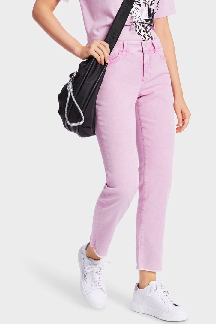 Jeans SIKAR rose, coupe slim à taille basse, avec un t-shirt graphique et sac noir, chaussures blanches.