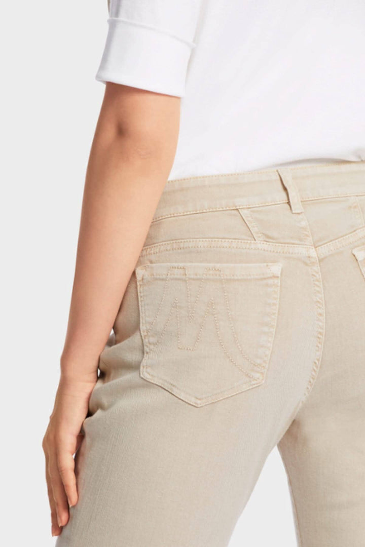 Femme portant des jeans beige SIKAR à cinq poches, montrant le dos et les détails de la coupe.