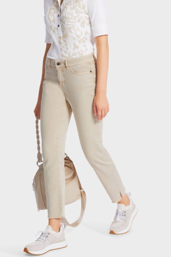 Femme portant des jeans SIKAR en denim stretch beige avec un t-shirt blanc et des baskets blanches.