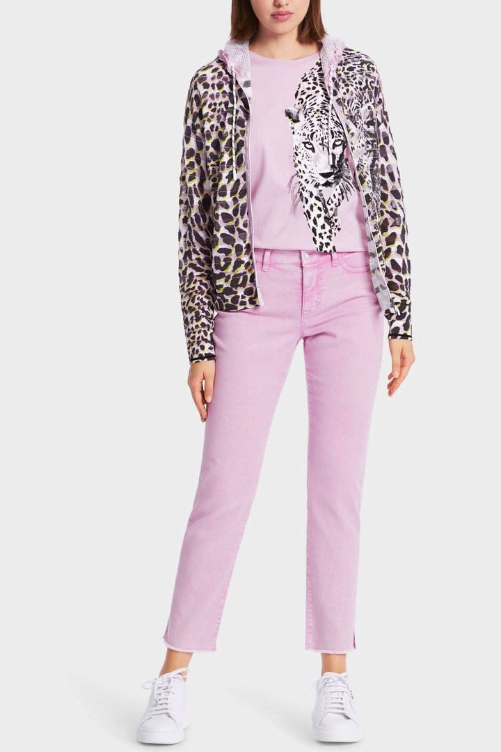 Femme portant une veste à imprimé léopard, t-shirt rose avec motif de léopard, et jeans roses.