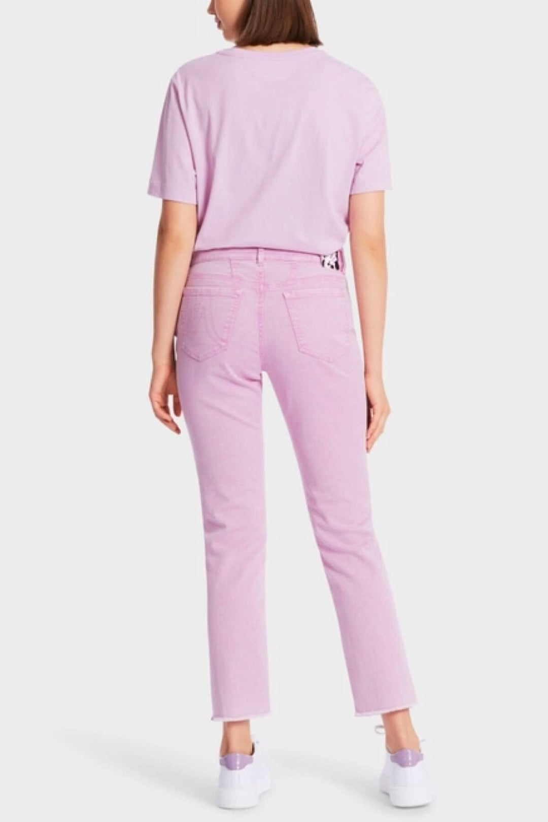 Femme portant un t-shirt rose et des jeans SIKAR roses, vue de dos, style décontracté.