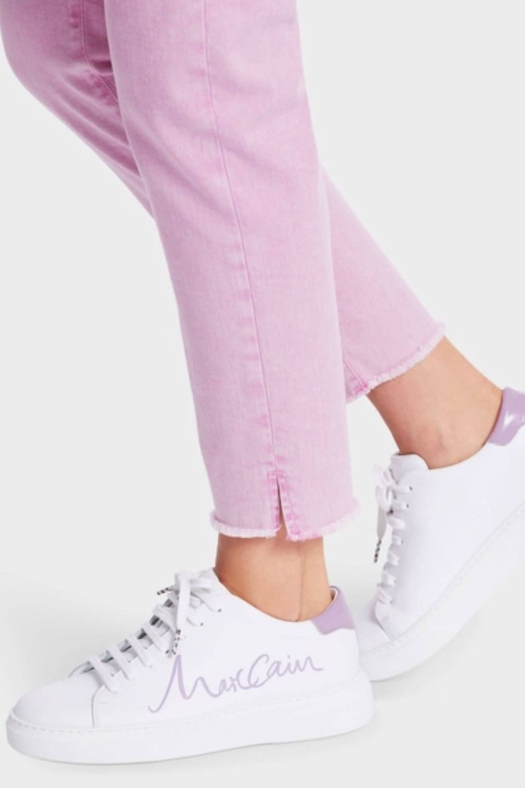 Femme portant des jeans roses avec des baskets blanches et violettes de la marque MaxCaini.