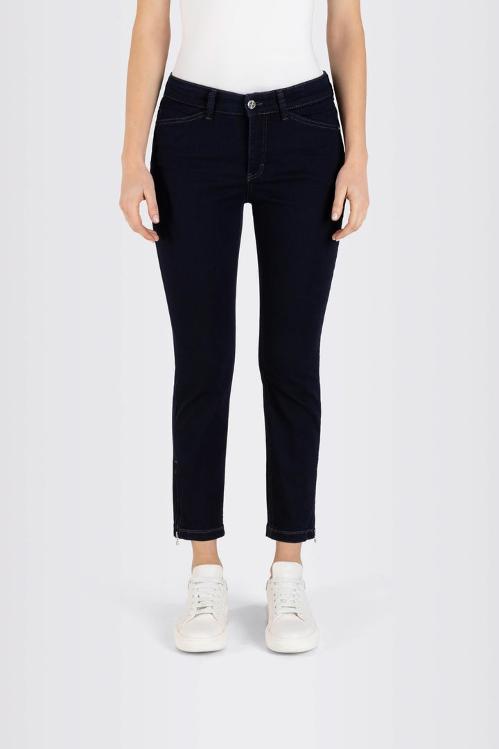 Jeans coupe ajustée longueur 7/8 en tissu extensible, taille régulière, fermés par bouton et fermeture éclair, avec sneakers blancs.