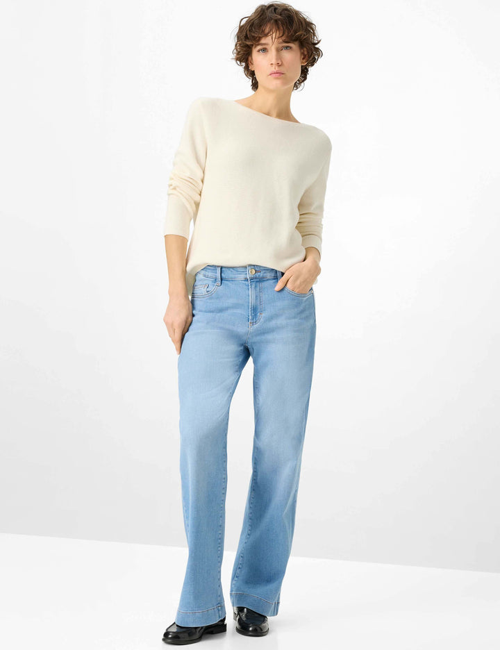 Jeans droit taille haute MAINE, coupe droite et taille haute, apportant élégance et confort, porté avec un pull blanc et chaussures noires.