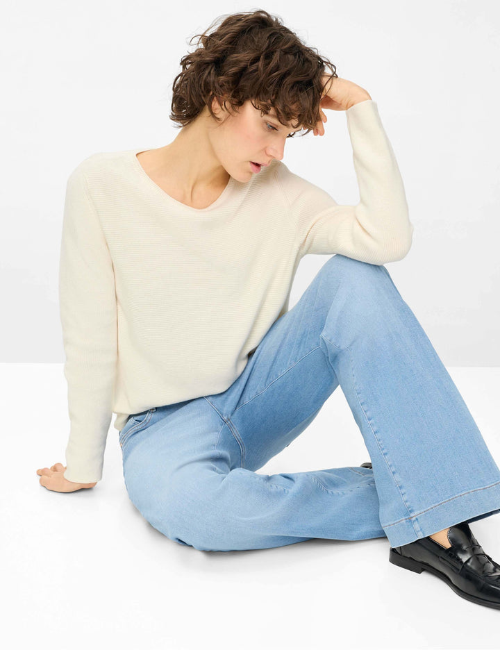 Jeans droit taille haute MAINE porté par une femme assise, avec un chandail blanc et des chaussures noires, style décontracté.