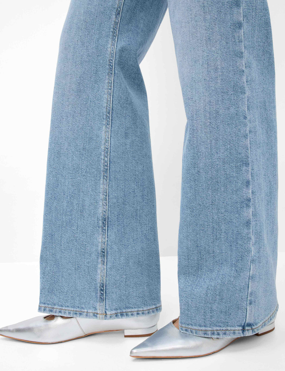 Pantalon palazzo en denim bleu avec des chaussures argentées, mettant en avant une coupe évasée et tendance.