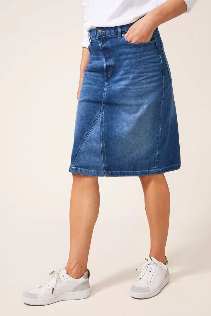 Jupe midi en jean, coupe classique, portée avec des baskets blanches, style décontracté et chic.