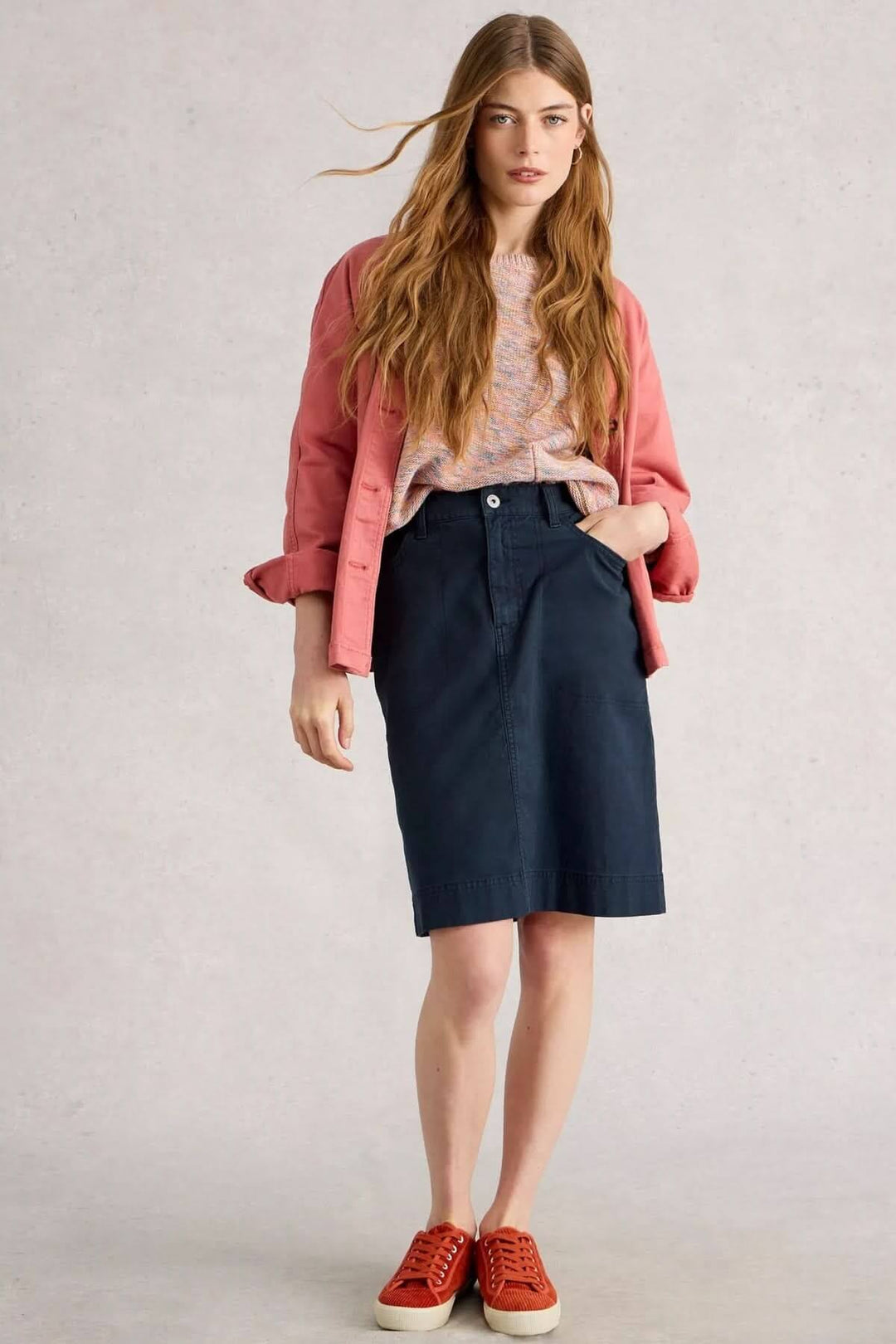 Femme portant une jupe droite Tia à taille haute avec un chandail coloré et des baskets, look urbain chic.