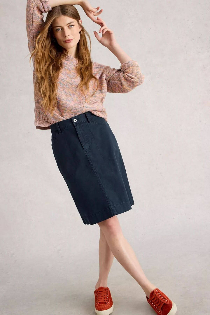 Femme en jupe droite taille haute, haut coloré et baskets, style urbain chic, coupe structurée, tissu souple.