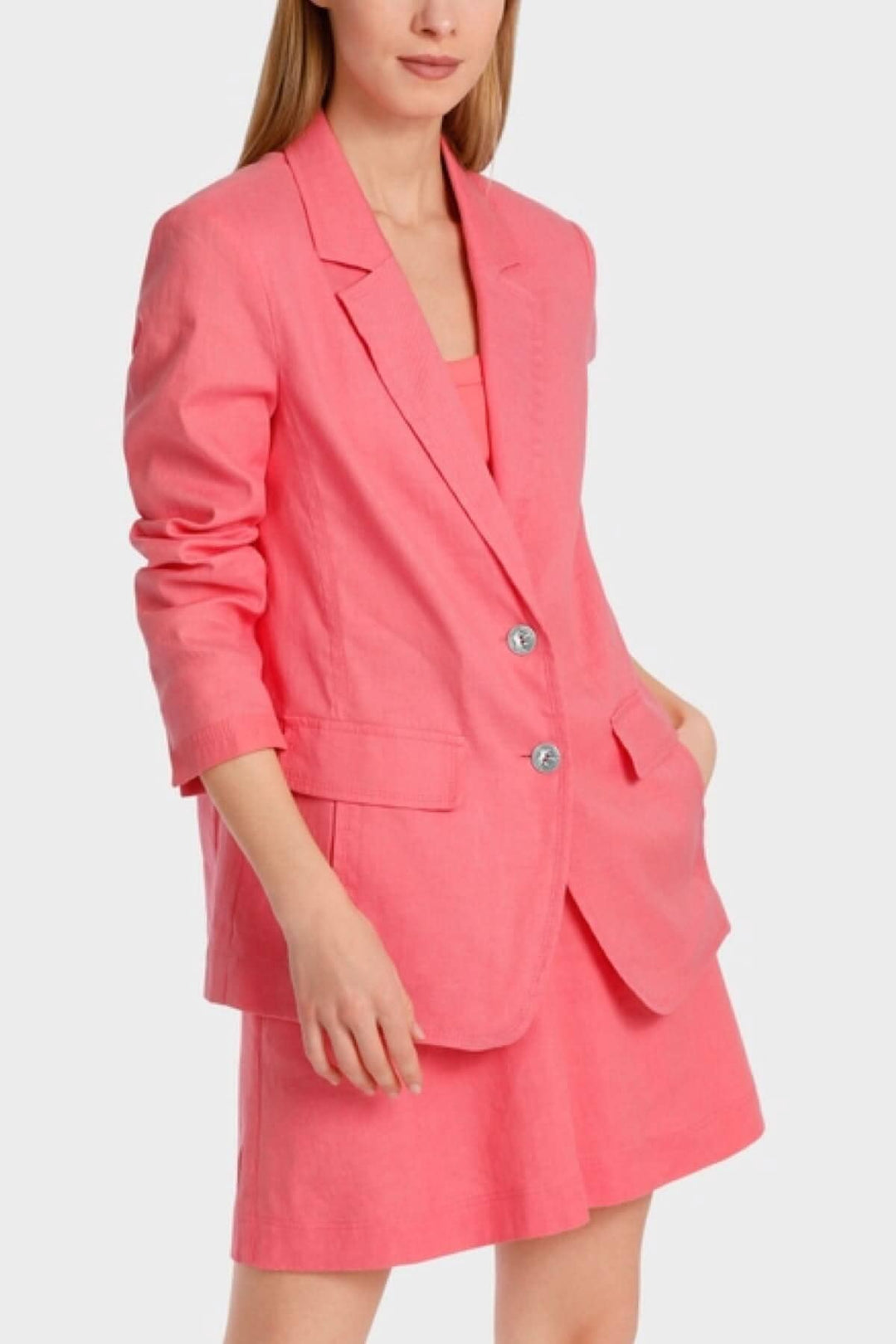Femme portant un blazer rose vif sur une jupe assortie, style décontracté et élégant, parfait pour l&