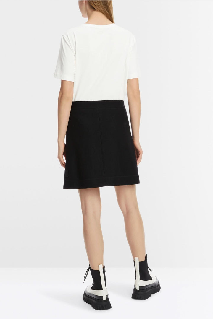 Femme vue de dos portant une mini-jupe noire avec un t-shirt blanc, style décontracté et moderne.
