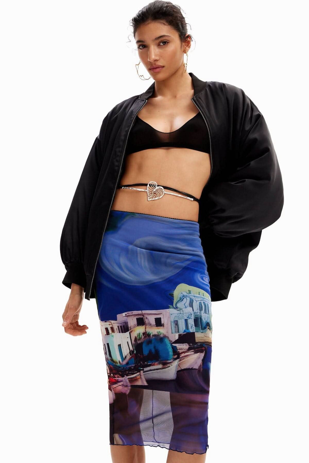 Femme portant une jupe midi imprimée paysage en tulle avec un bomber noir et un haut noir.
