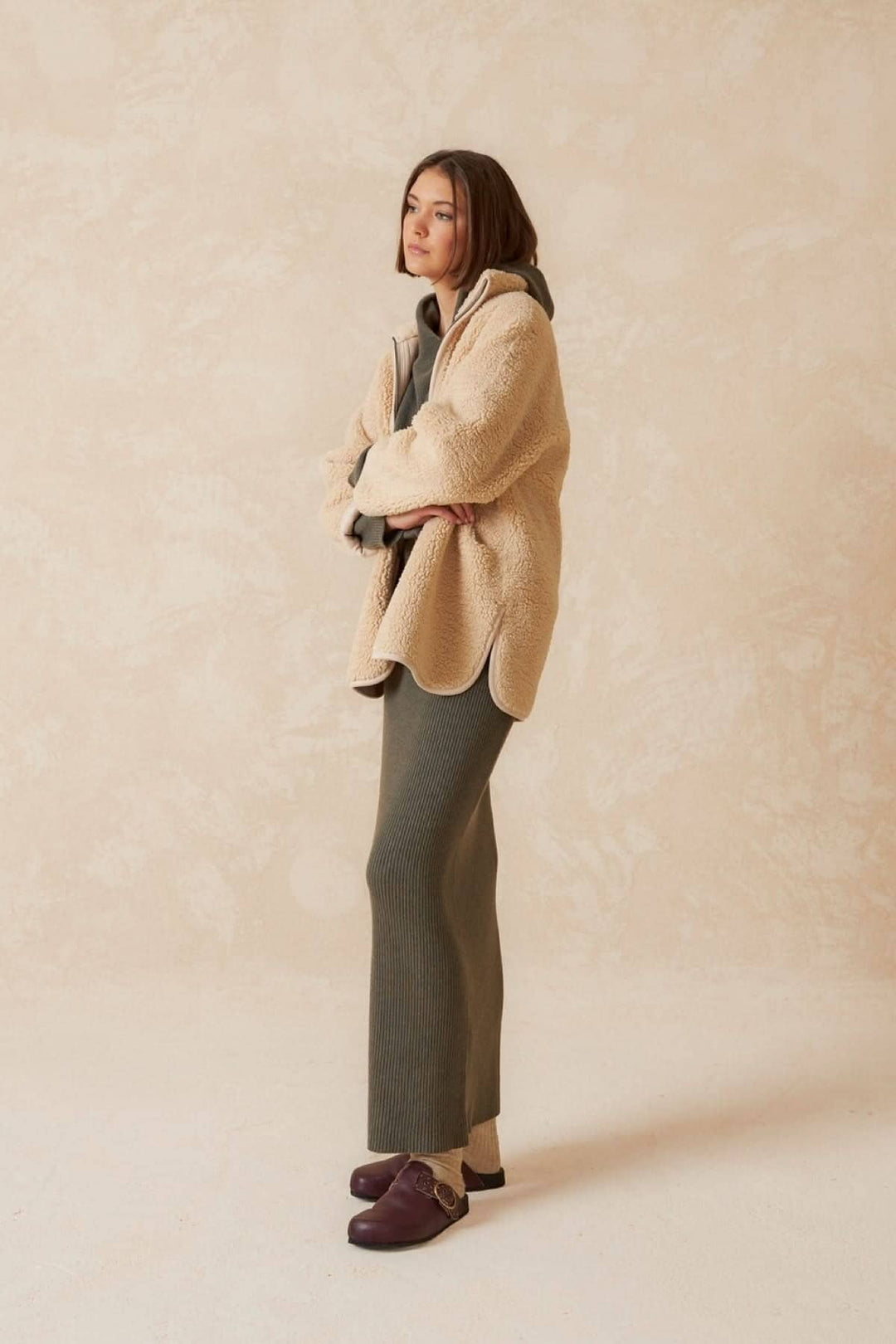 Femme portant une jupe longue confortable et un haut en peluche, style décontracté et chic, sur fond neutre.