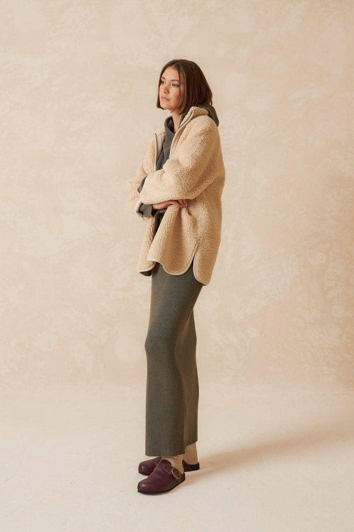 Femme portant une jupe longue confortable et un haut en peluche, style décontracté et chic, sur fond neutre.