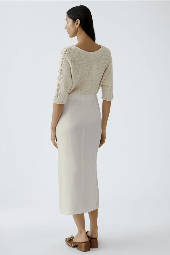Femme vue de dos, portant une jupe longue en lin et un haut beige, parfaite pour une tenue d&