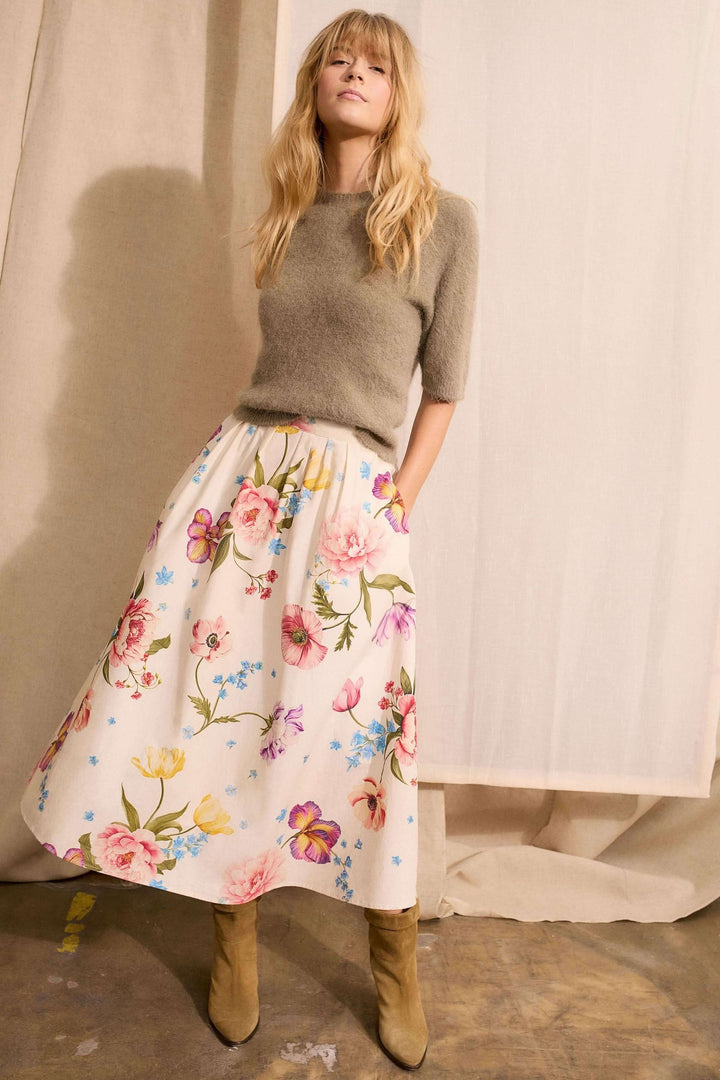 Jupe mi-longue imprimé de fleurs avec silhouette fluide et taille structurée, associée à un pull simple pour un look élégant.