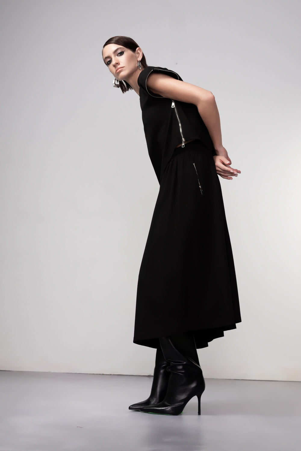 Jupe midi coupe fluide noire portée avec élégance, silhouette asymétrique, style contemporain et polyvalent.