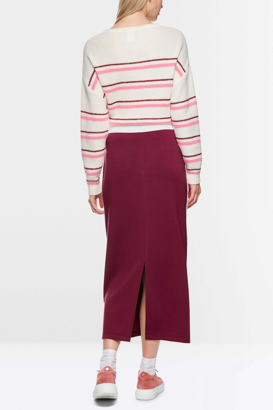 Femme portant une jupe midi sportive bordeaux avec fente arrière, bandes contrastées et logo Marc Cain Sports sur la poche.