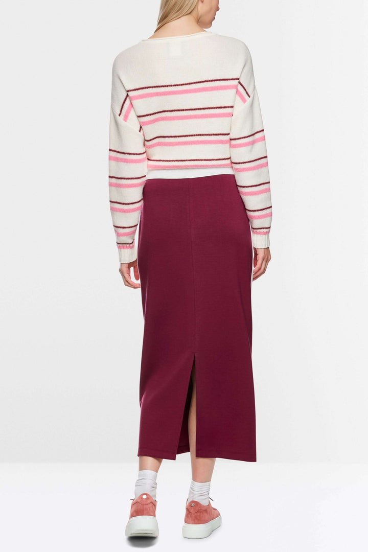 Femme portant une jupe midi sportive bordeaux avec fente arrière, bandes contrastées et logo Marc Cain Sports sur la poche.