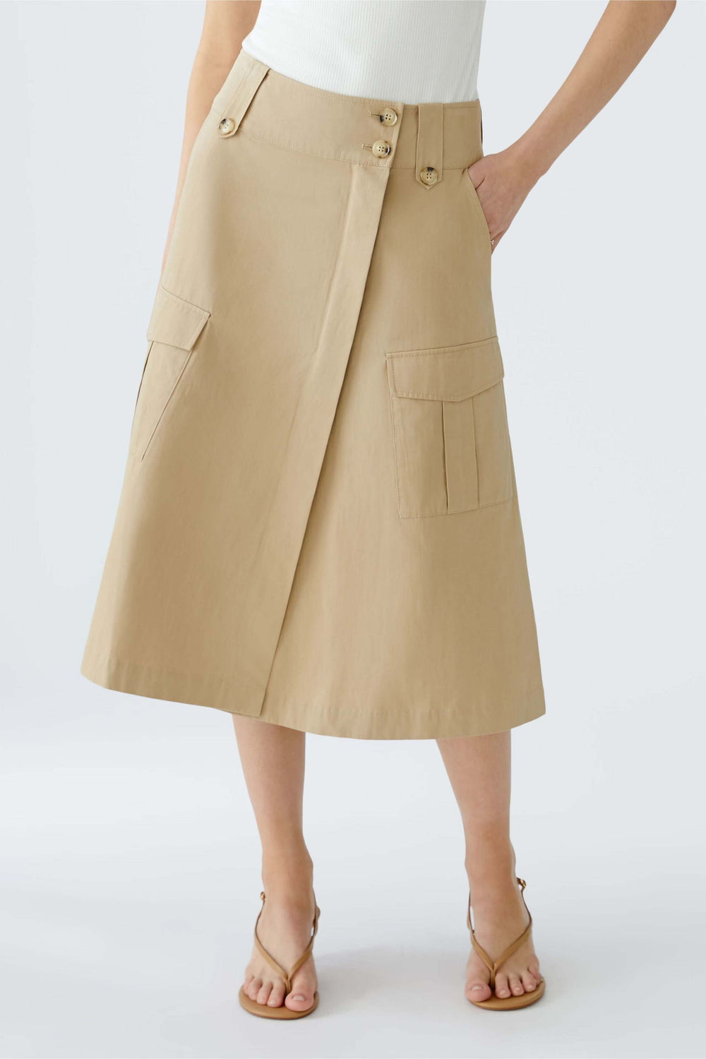 Jupe portefeuille en coupe trapèze beige avec grandes poches, ceinture et style moderne.