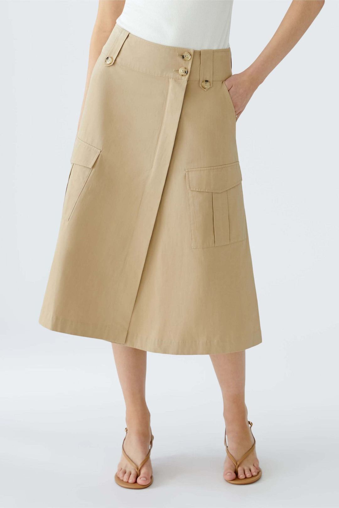 Jupe portefeuille en coupe trapèze beige avec grandes poches, ceinture et style moderne.