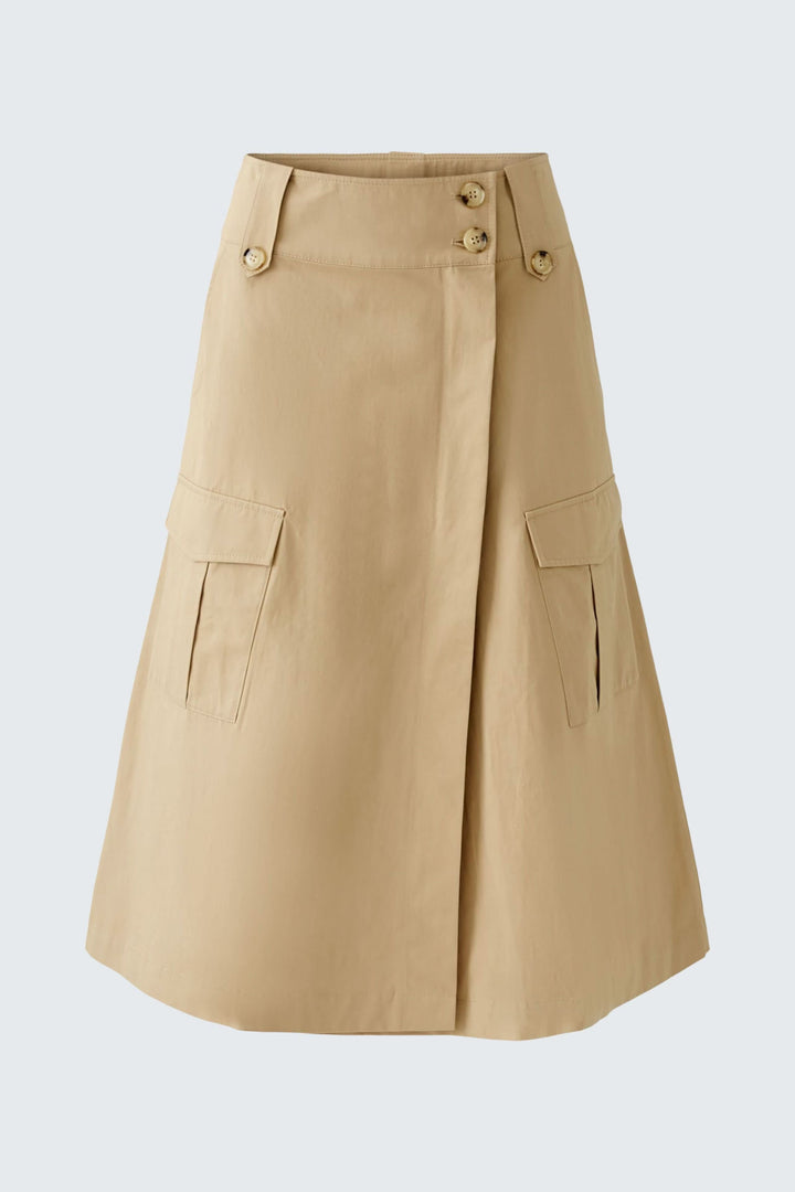 Jupe portefeuille en coupe trapèze beige avec poches, boutons et ceinture, style safari moderne.