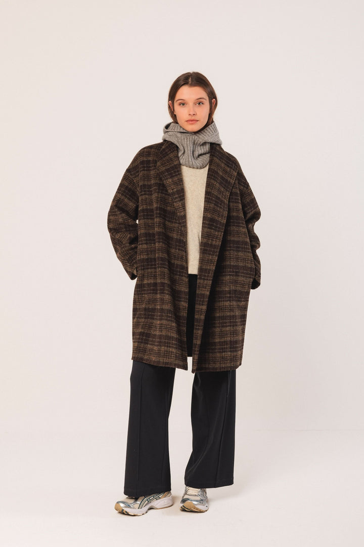 Manteau à carreaux oversize, chic et décontracté, porté avec un pull et un pantalon fluide.