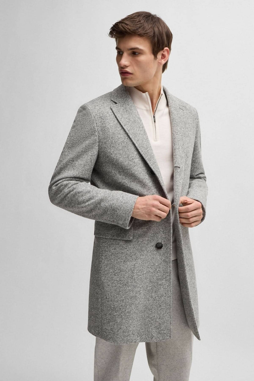 Manteau à chevrons gris pour homme, coupe ajustée, avec fermeture amovible, style élégant et moderne.