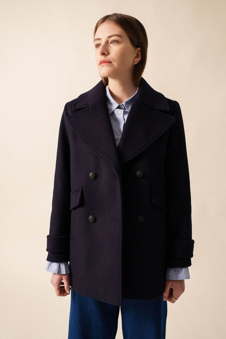 Femme portant un manteau chic STE ROMY, longueur sous les fesses, col en V, boutons à l&
