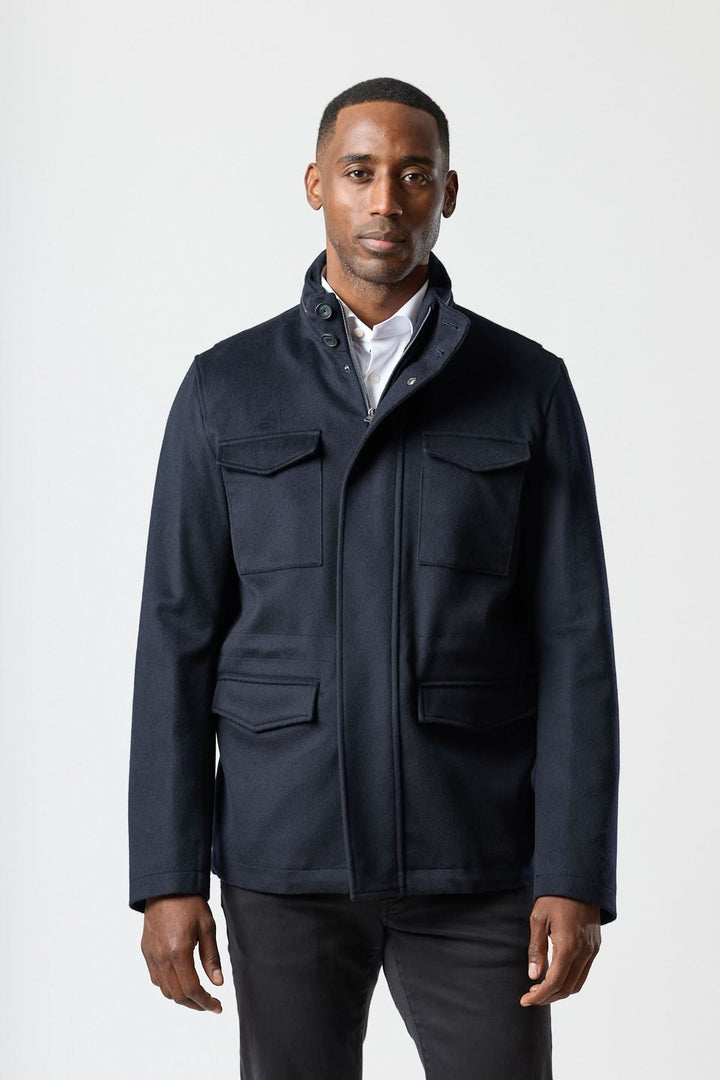 Homme portant un manteau en laine à quatre poches, style field jacket, couleur sombre, pour un look smart-casual soigné.