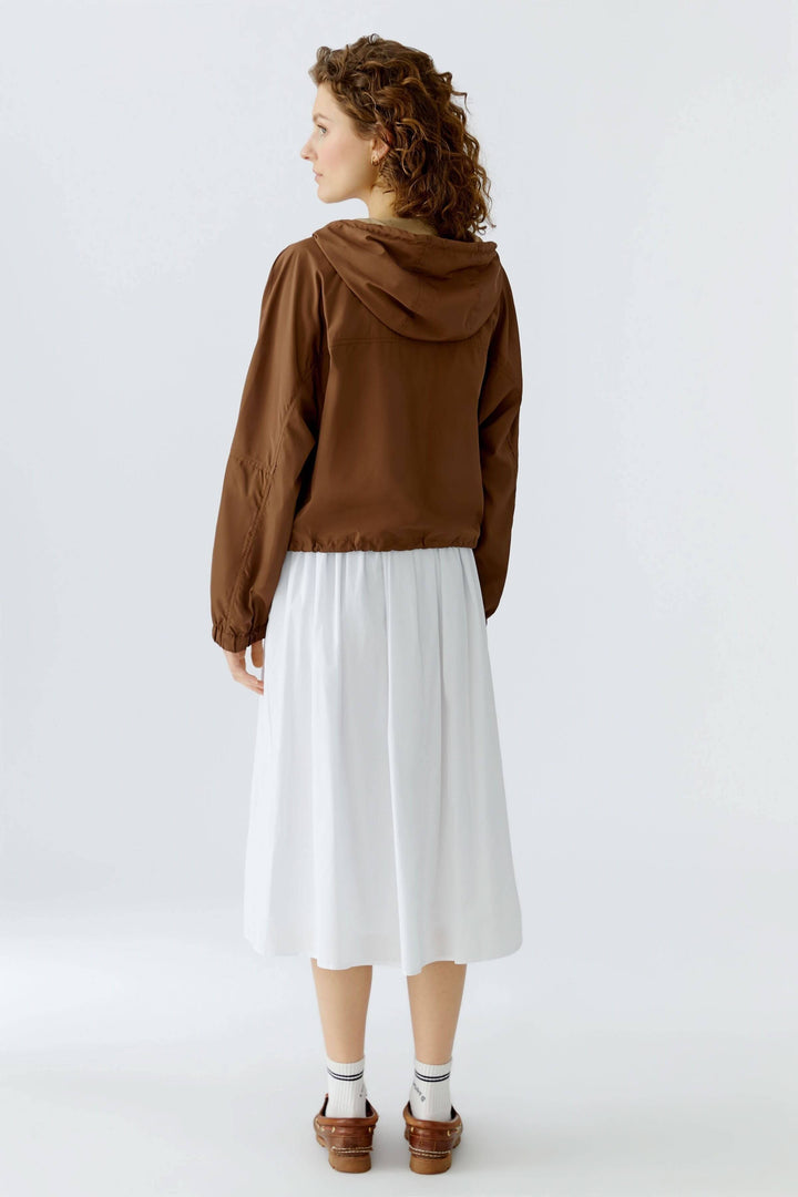 Femme portant un manteau léger à capuchon marron, coupe ample, parfait pour mi-saison, vue arrière, style urbain et décontracté.