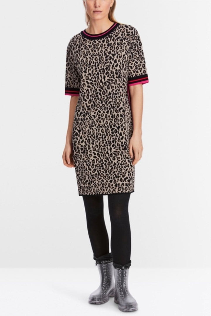 Mini-robe en tricot léopard avec manches courtes et bordures colorées, portée avec des bottes transparentes.