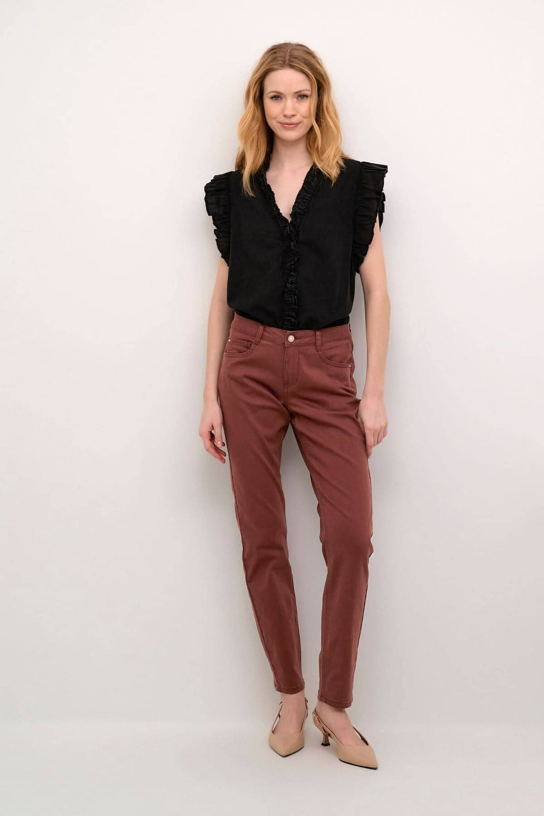 Femme portant un pantalon rouge et un haut noir, mettant en valeur une coupe régulière et des détails élégants.