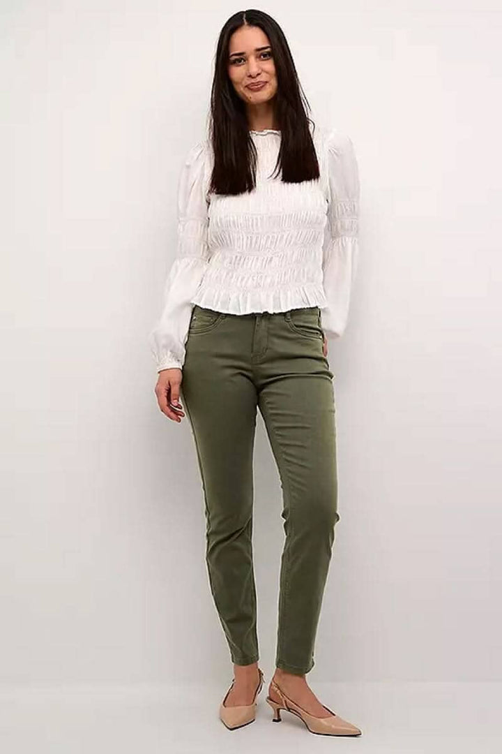Pantalon Ann pleine longueur en coton, coupe régulière, porté avec un haut blanc et des talons.