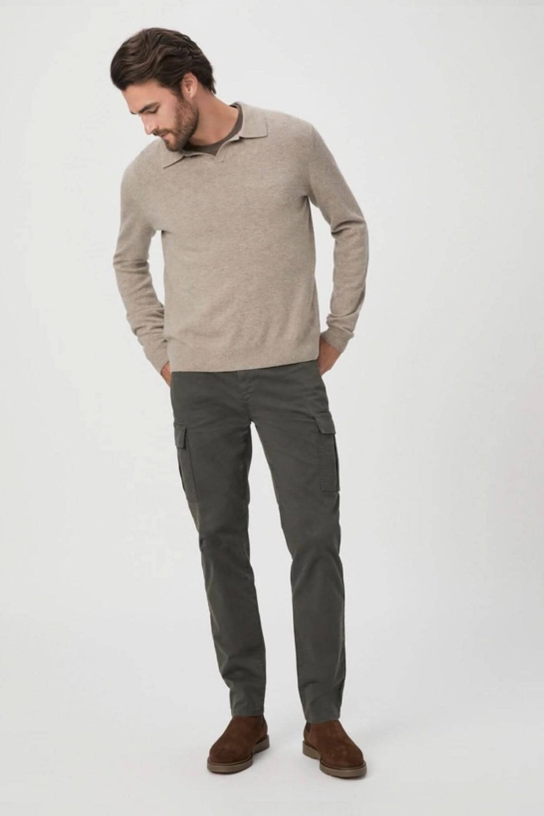 Homme portant un pull beige et un pantalon cargo noir, style décontracté et élégant.