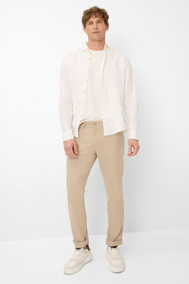 Homme portant un Pantalon Chuck beige avec coupe droite, chemise blanche et baskets, illustrant un look moderne et décontracté.